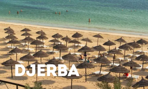 Strand von Djerba mit hellem Wasser und vielen Sonnenschirmen