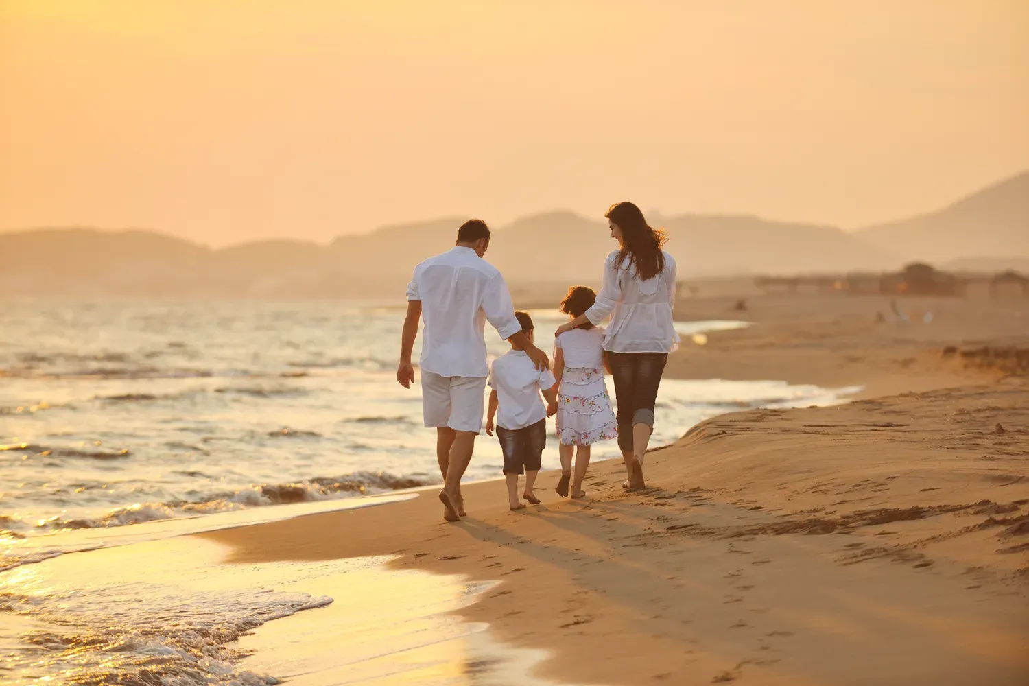 Mann, Frau und zwei Kinder von hinten fotografiert am Strand