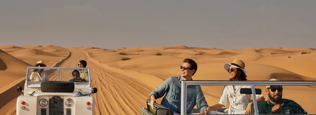 Zwei Familien in zwei weißen Autos fahren durch die Dünen in Dubai
